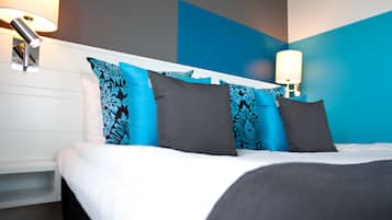 A neatly made bed with white and grey linens, blue patterned pillows, and a modern headboard.
