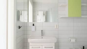 A modern bathroom with a white sink, a mirror, a towel rack, and a green cabinet.