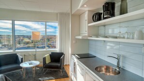 A modern kitchen with a stainless steel sink, white cabinets, and a city view through large windows. - Sky Hotel Apartments Tornet (Linkoping)