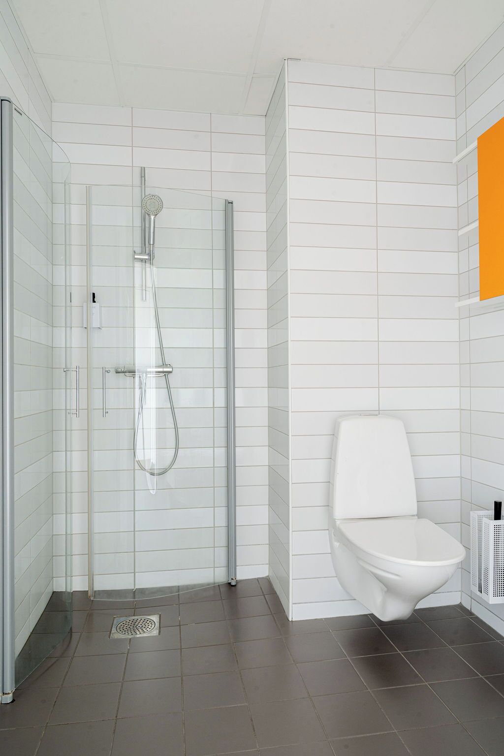 A modern bathroom with a glass-enclosed shower, a white toilet, and a tiled floor.