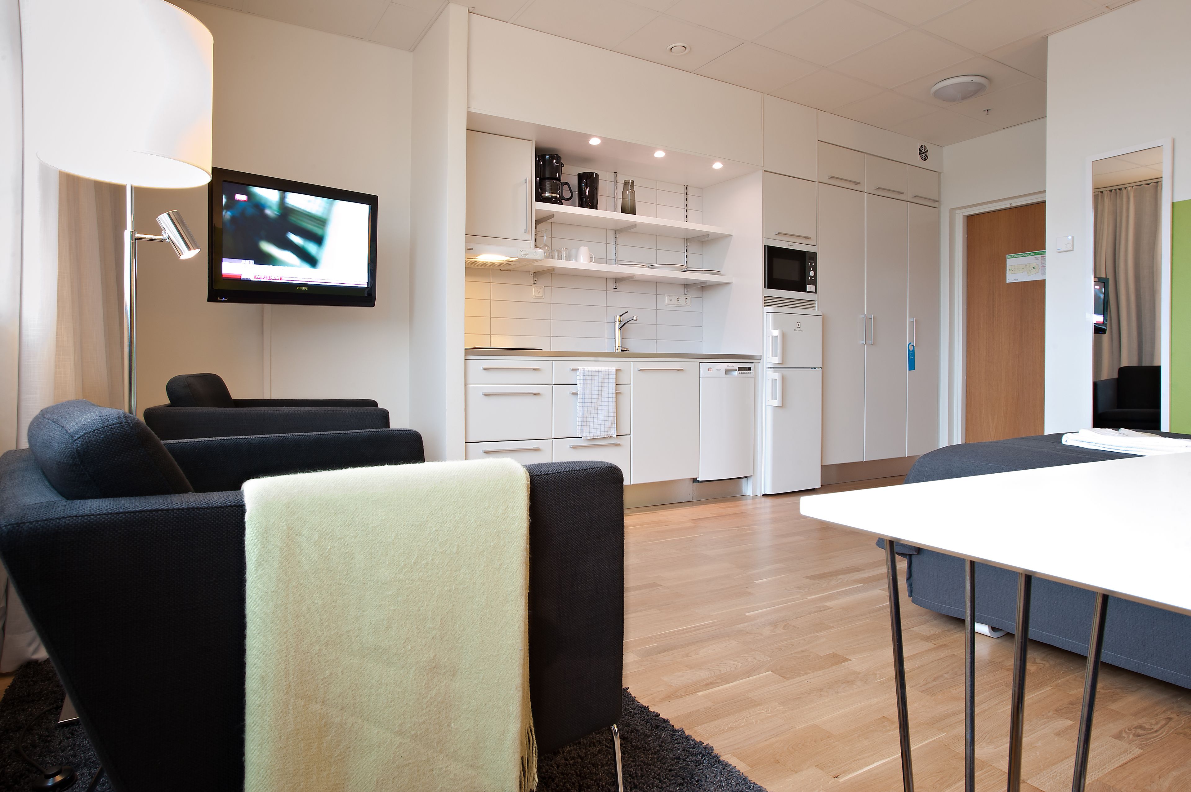 A modern living room with a flat-screen TV, a sofa, and a dining table.