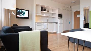A modern living room with a flat-screen TV, a sofa, and a dining table.