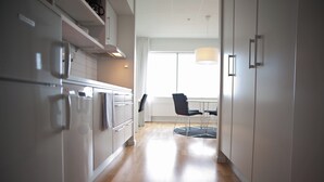 A modern kitchen with white cabinets, a built-in oven, and a dining area with a table and chairs. - Sky Hotel Apartments Tornet (Linkoping)