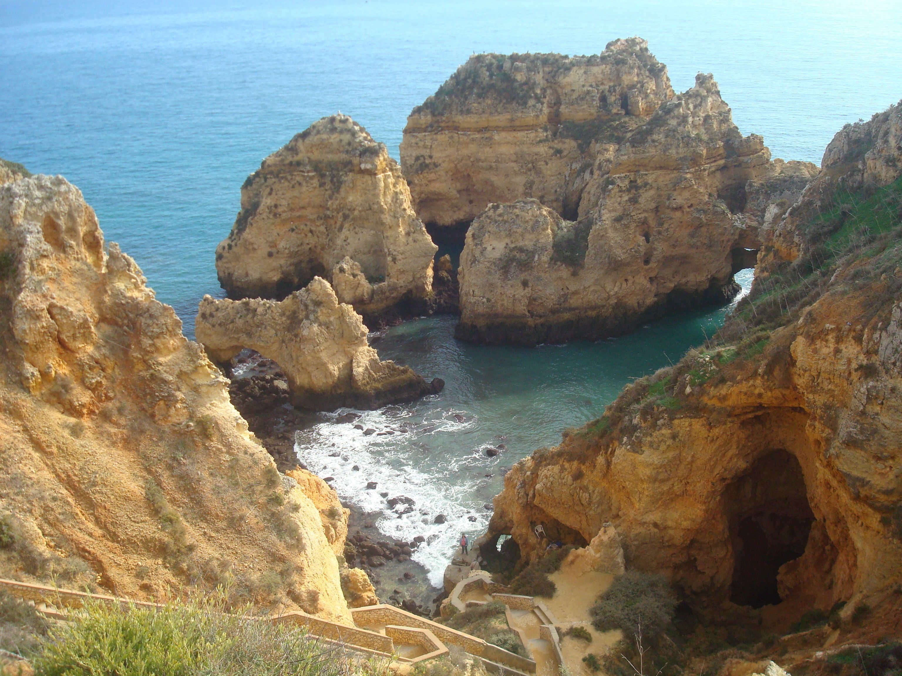 A coastal landscape with rocky cliffs and a clear view of the sea.