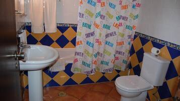 Un bagno con lavandino, wc e tenda per la doccia.