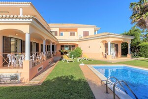 Ein zweistöckiges Gebäude mit Swimmingpool, Sitzgelegenheit im Freien und einem gepflegten Rasen.