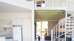 A dining area with a wooden table, beige chairs, a candle, and a menu. - Shelly Beach Resort (Port Macquarie)