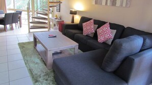 A living room with a sofa, coffee table, and a staircase leading to an upper floor. - Shelly Beach Resort (Port Macquarie)