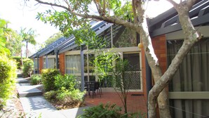 A courtyard with a brick pathway, a table and chairs, and various plants. - Shelly Beach Resort (Port Macquarie)