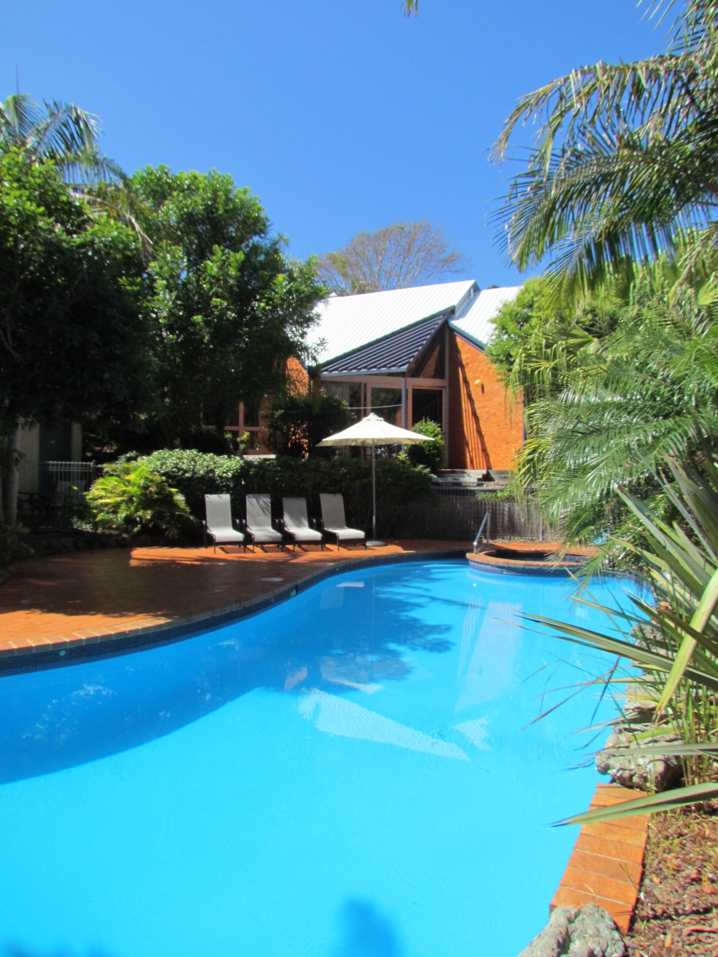 A swimming pool with lounge chairs and an umbrella.