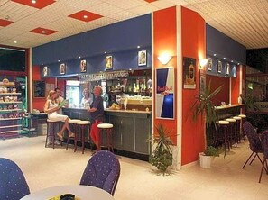 A bar area with stools and a counter, surrounded by tables and chairs. - Glarus (Nessebar)