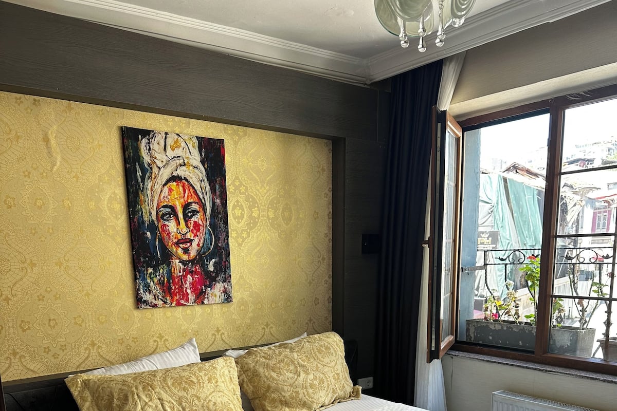 Habitación de hotel con una cama grande, un cuadro en la pared y una ventana con vistas al exterior.