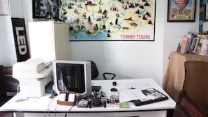 Un escritorio con una computadora, una impresora y diversos útiles de oficina. Un mapa titulado