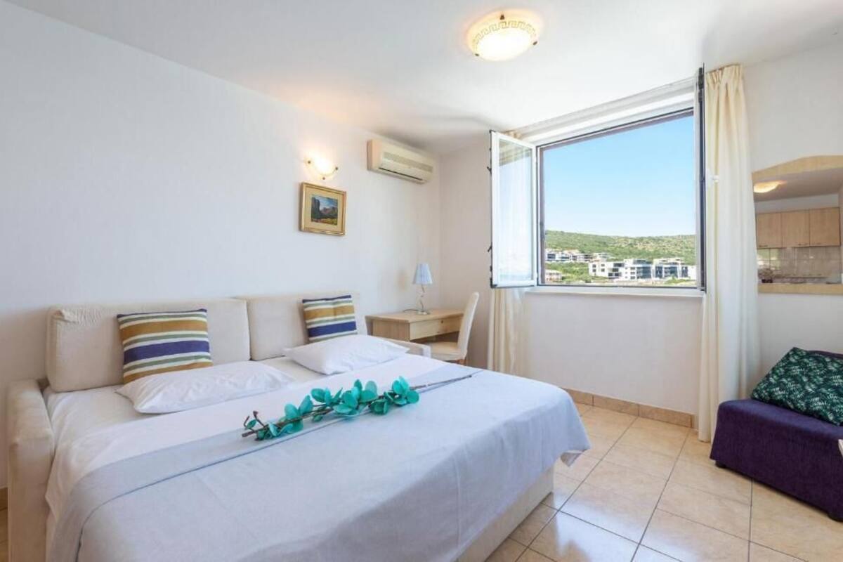 Hotellihuone, jossa on suuri sänky, työpöytä, tuoli ja suuri ikkuna, josta avautuu näkymä kaupunkiin.