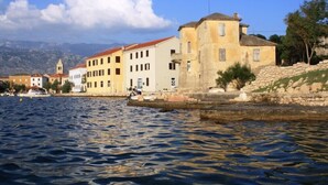 A coastal town with buildings along the waterfront, a stone wall, and a body of water. - Tamarix Residence (Posedarje)