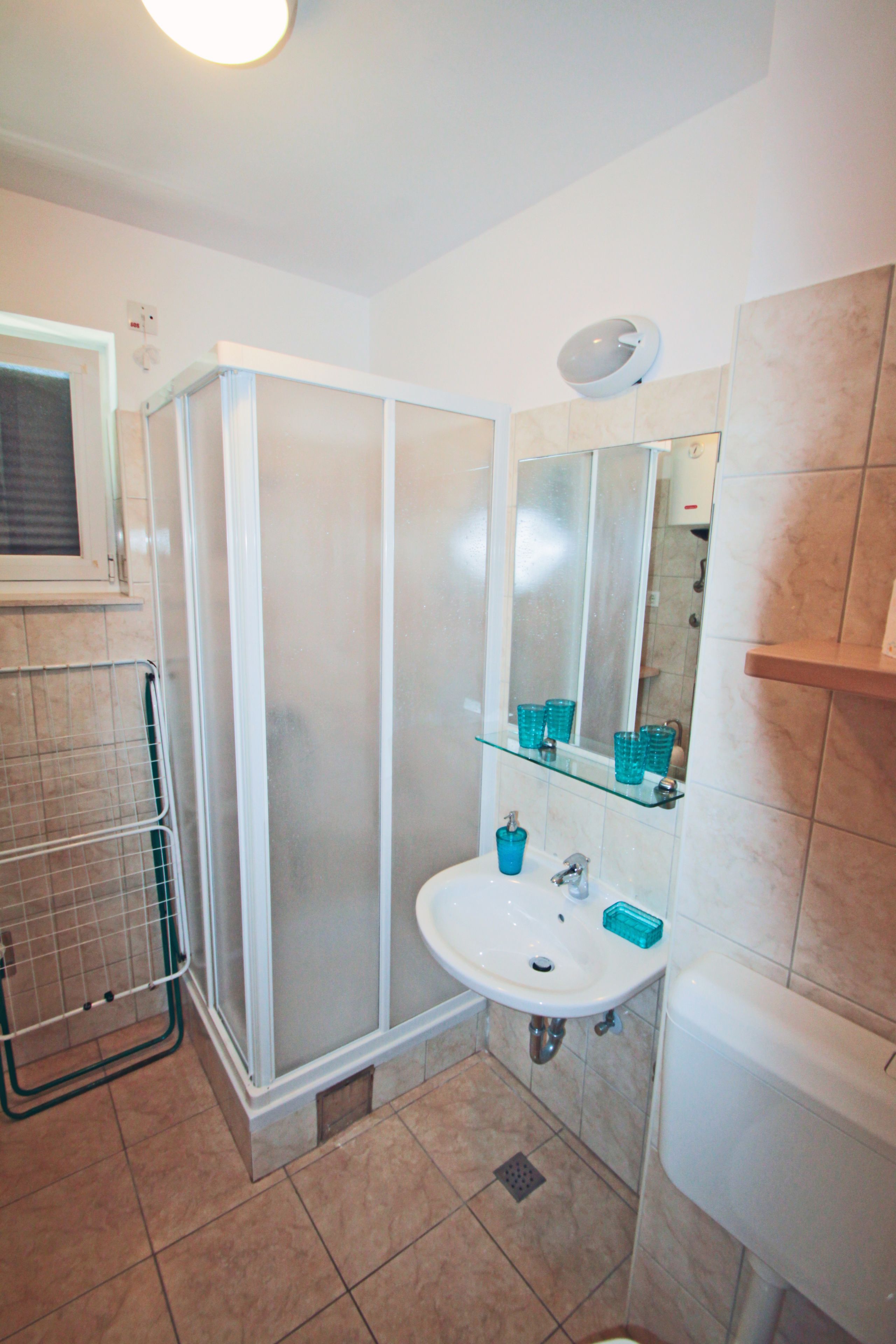 A bathroom with a glass shower enclosure, a sink with a mirror above it, and a toilet.