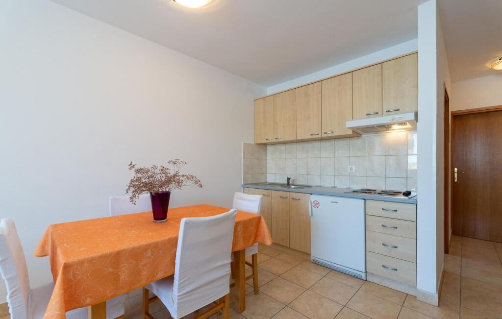 Eine kleine Küche mit Holzschränken, einer weißen Arbeitsplatte und einer gefliesten Spritzschutzwand.