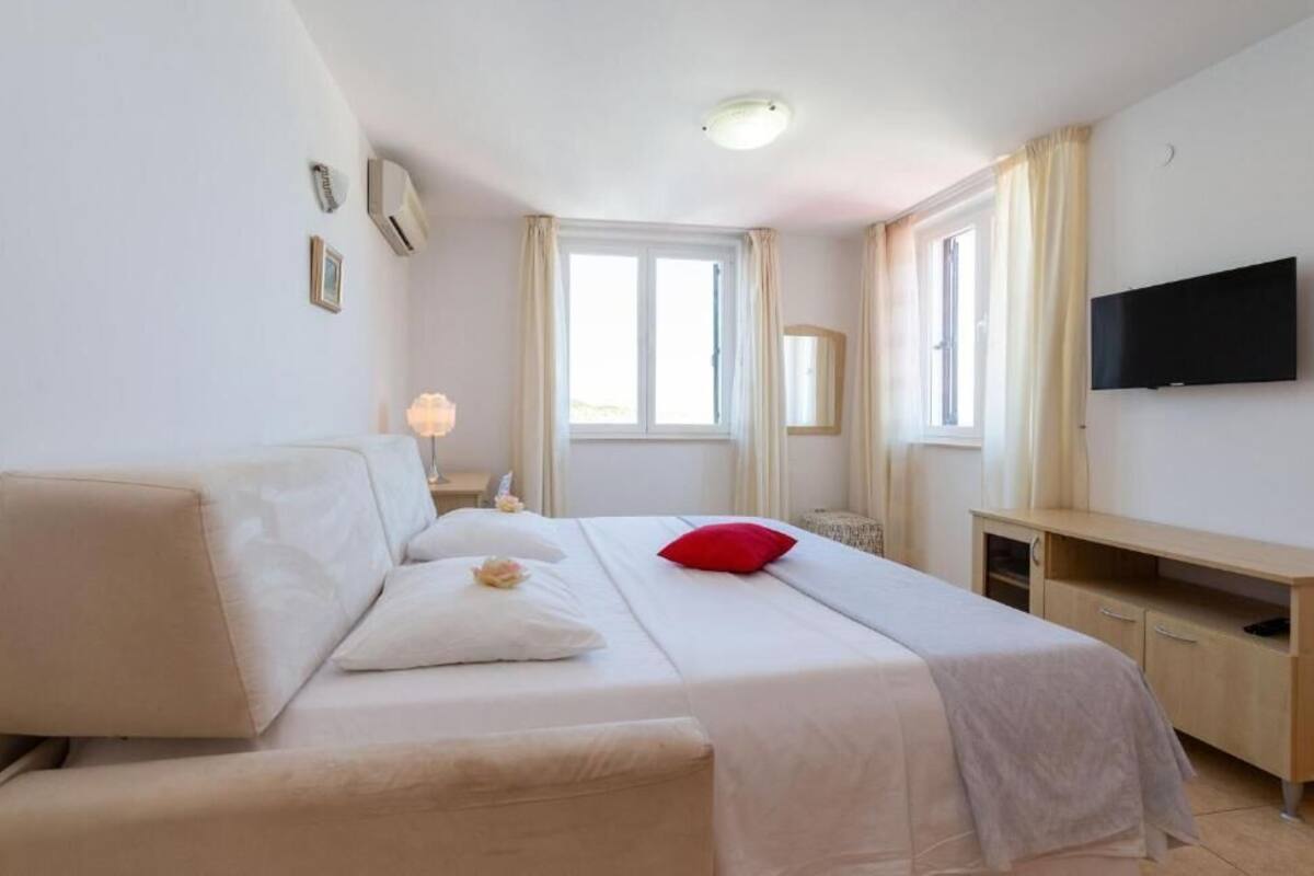 Hotellihuone, jossa on sänky, työpöytä, televisio ja ikkuna.