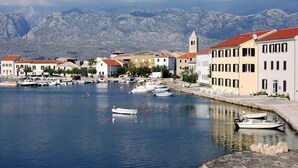 A coastal town with a marina, buildings with red roofs, and a mountain backdrop. - Tamarix Residence (Posedarje)