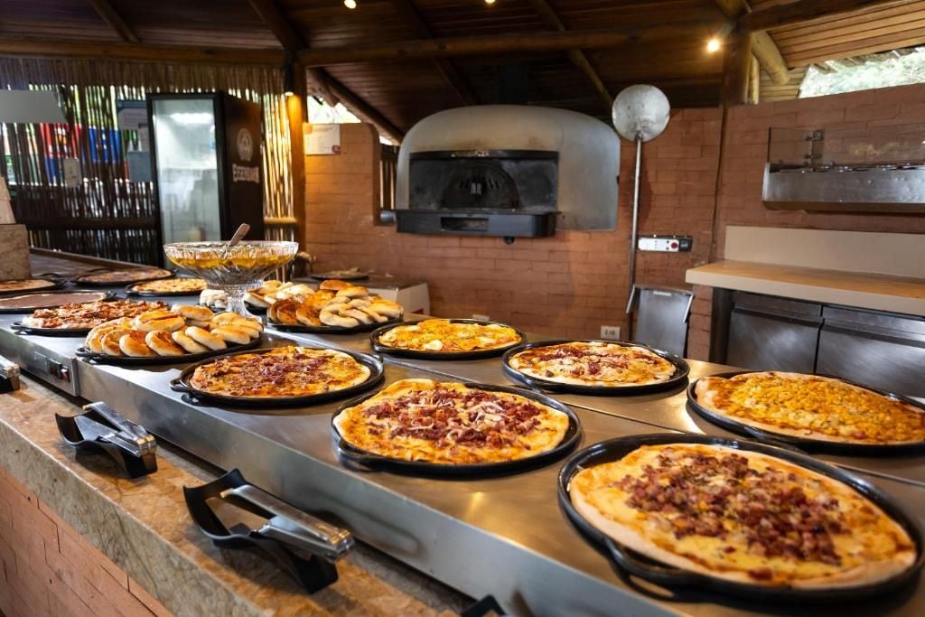 A pizza station with multiple pizza pans and a brick oven.