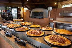En pizzastation med flere pizzabakker og en murstensovn.