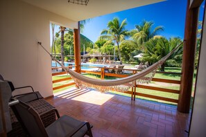 A hammock on a balcony with a pool view, outdoor seating, and a clear sky. - La Torre Resort All Inclusive (Porto Seguro)