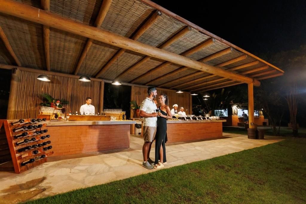 Uma área de bar ao ar livre com estrutura de madeira, balcão e adega.