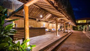 A wooden structure with a thatched roof, a reception desk, and outdoor seating. - La Torre Resort All Inclusive (Porto Seguro)