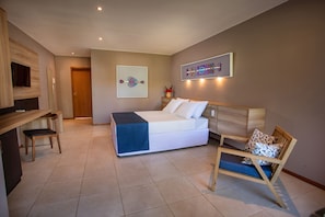 A modern bedroom with a bed, a chair, a desk, and artwork on the walls.