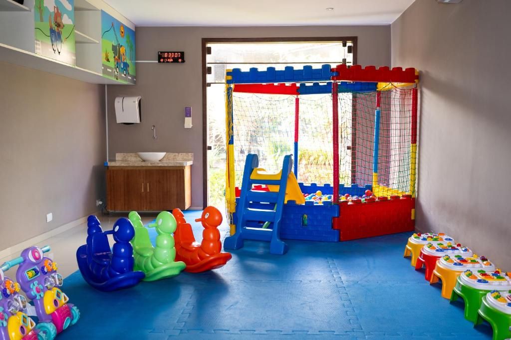 Espaço de recreação infantil com brinquedos coloridos e janela para o exterior.