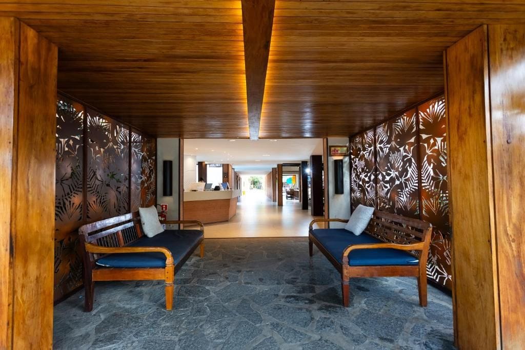Un área de recepción con bancos de madera, un mostrador de recepción y una pared con diseño.