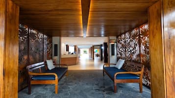 Un área de recepción con bancos de madera, un mostrador de recepción y una pared con diseño.