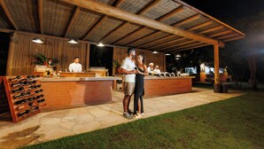 An outdoor bar area with a wooden ceiling, a counter with a wine rack, and a seating area. - La Torre Resort All Inclusive (Porto Seguro)