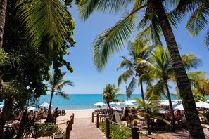 A beachside restaurant with outdoor seating, palm trees, and a view of the ocean. - La Torre Resort All Inclusive (Porto Seguro)