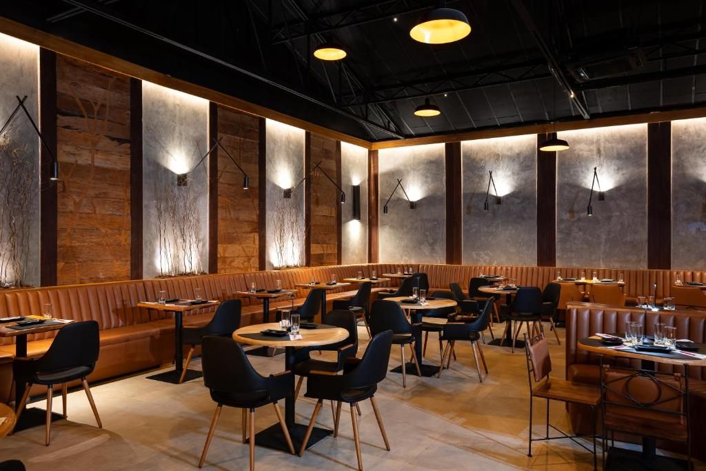 A restaurant interior with booths and tables, wooden accents, and pendant lighting.