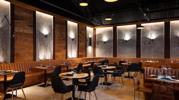 A restaurant interior with booths and tables, wooden accents, and pendant lighting.