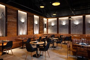 A restaurant interior with booths and tables, wooden accents, and pendant lighting. - La Torre Resort All Inclusive (Porto Seguro)