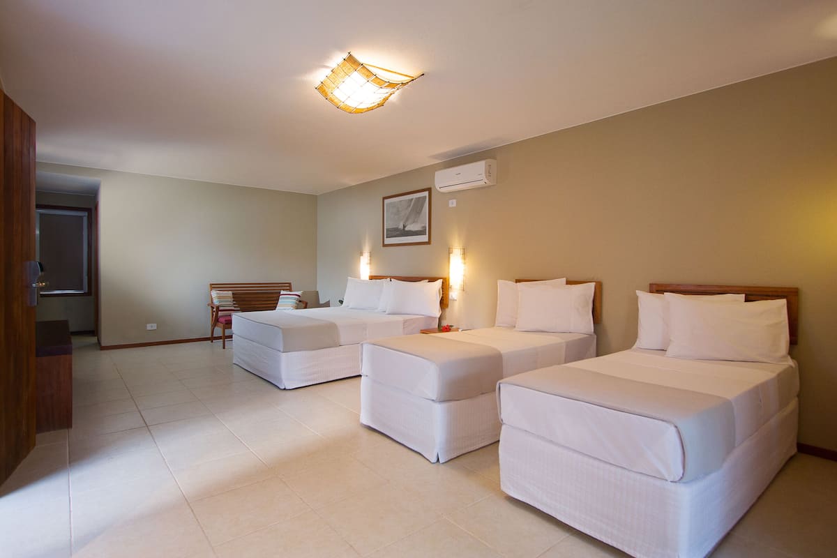 A hotel room with two single beds, a wooden chair, a small table, and a ceiling light fixture.