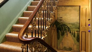 A staircase with ornate metal railings and a carpeted landing.