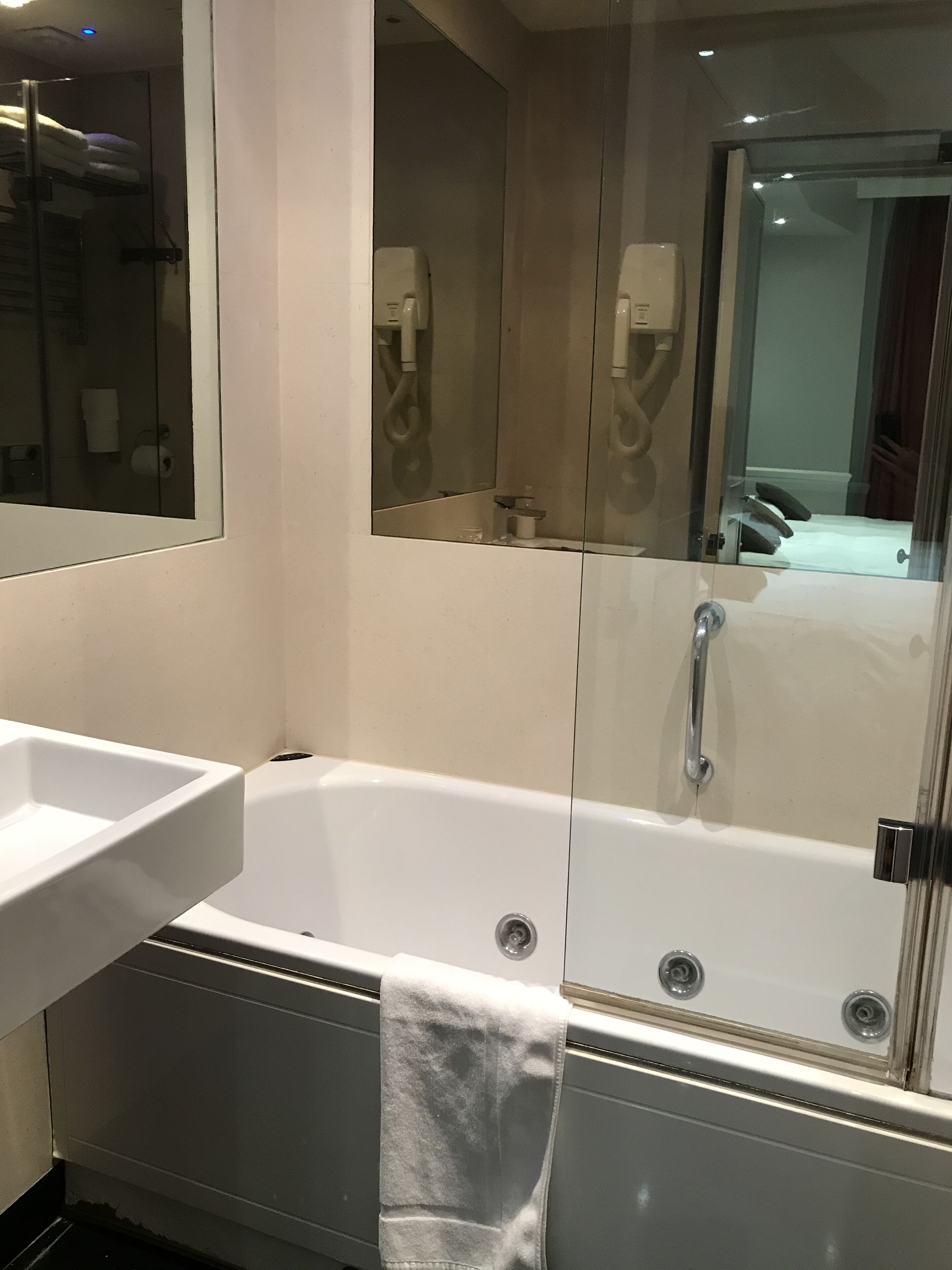 A modern bathroom with a white bathtub, a sink, and a large mirror.