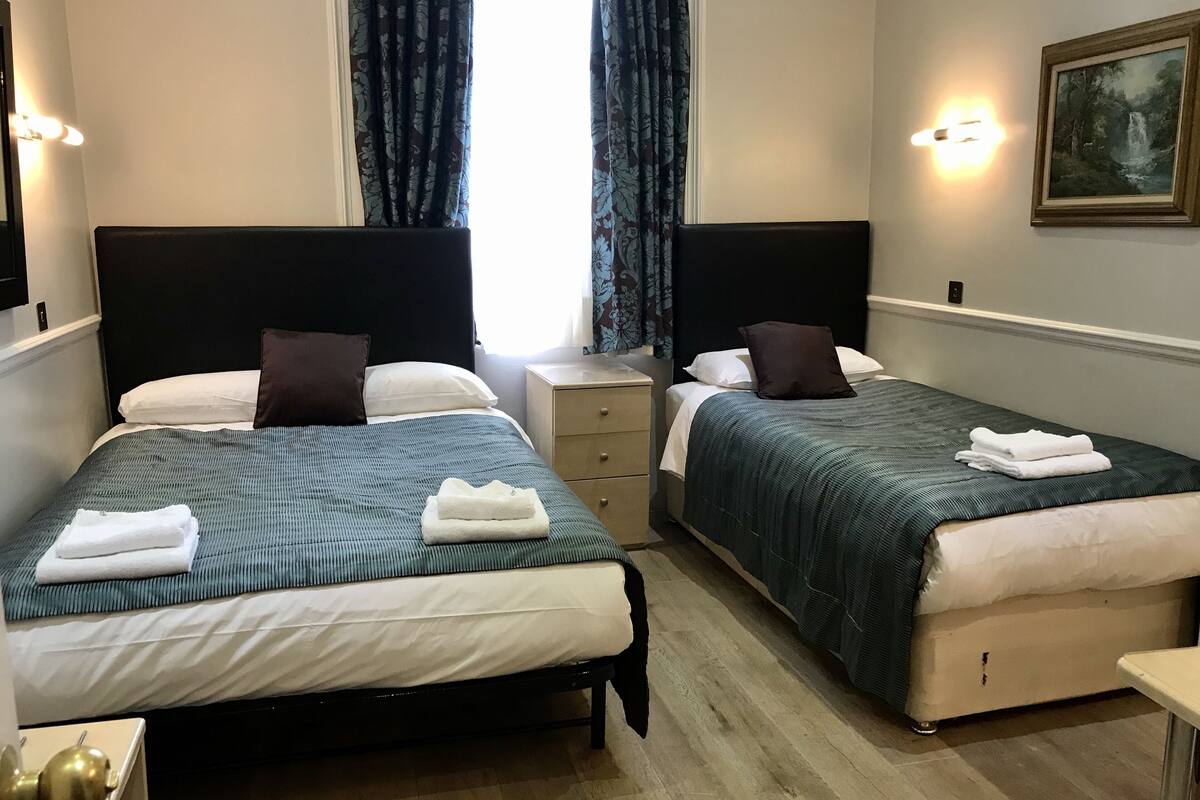 Une chambre d’hôtel avec deux lits, chacun étant équipé d’un oreiller, d’une table de chevet et d’une lampe.