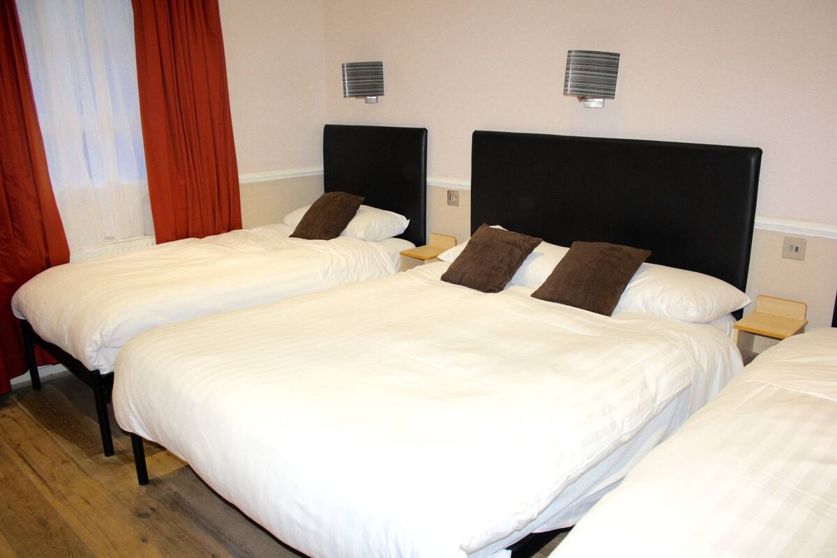 Une chambre d’hôtel avec deux lits simples, chacun doté d’une table de chevet en bois et d’une lampe.