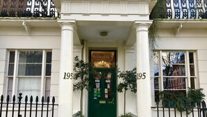 A hotel entrance with a green door, white columns, and a checkered floor.