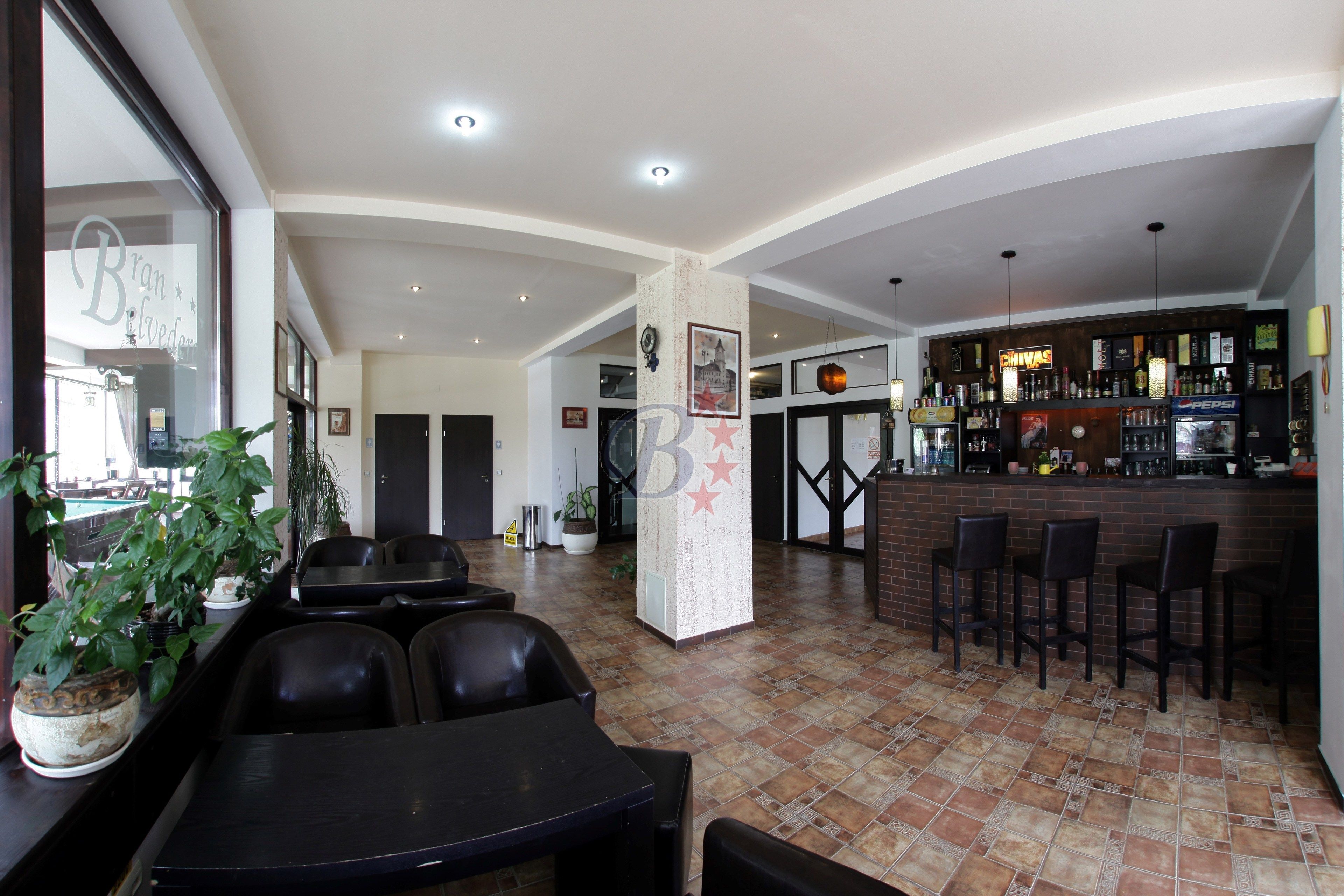 A restaurant with a bar area, black chairs, and a tiled floor.