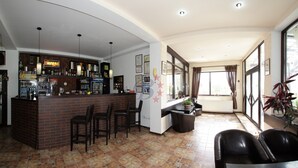 Uma área de bar com balcão de tijolos, várias cadeiras e piso ladrilhado.