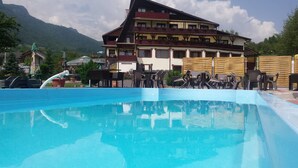 Piscina com espreguiçadeiras e um edifício ao fundo.