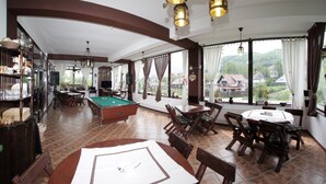 Um quarto espaçoso com mesa de bilhar, área de refeições e grandes janelas com vista para o campo.