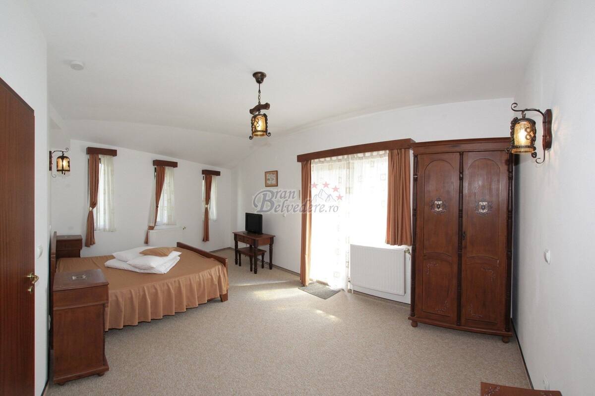 Une chambre avec deux lits, un bureau, une armoire et un radiateur.