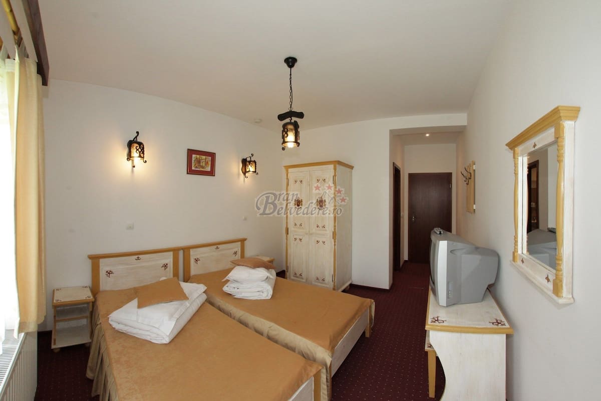 Une chambre d’hôtel avec deux lits, une armoire, une télévision et un miroir.