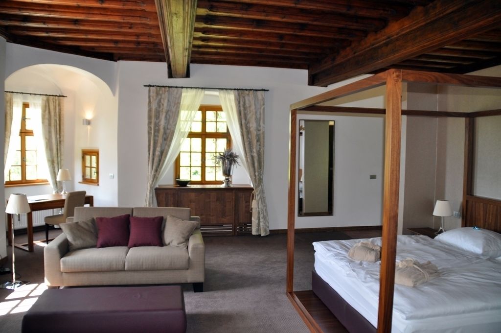 A bedroom with a four-poster bed, a sofa, a desk, and a chair.